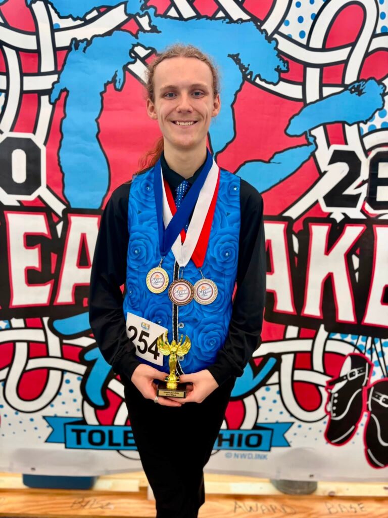Team BCA Irish dancer wearing a custom vest featuring Wylie Caudill's cerulean blue rose pattern while holding a trophy and medals at the Great Lakes Feis