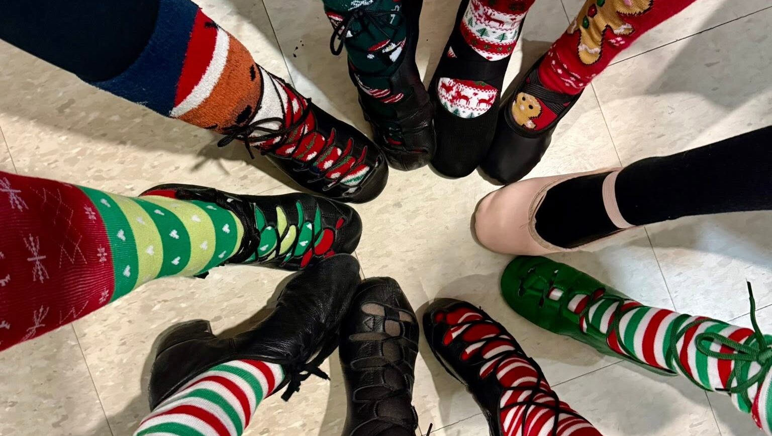 Irish dancers in a cirgle wearing holiday-themed socks pointing their toes.